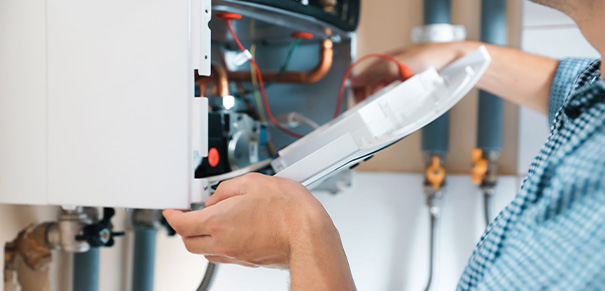 Technician servicing a boiler with tools and equipment in a home environment.