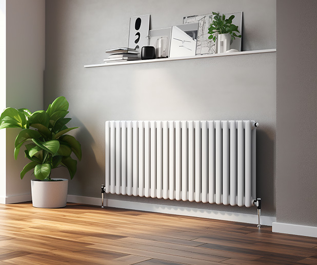 Stylish white radiator on a wooden floor with a green plant nearby