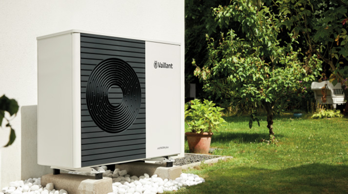 Air source heat pump installed in a garden setting with greenery.