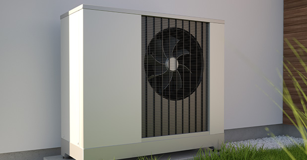 Outdoor heat pump unit against a neutral wall with grass and landscaping.